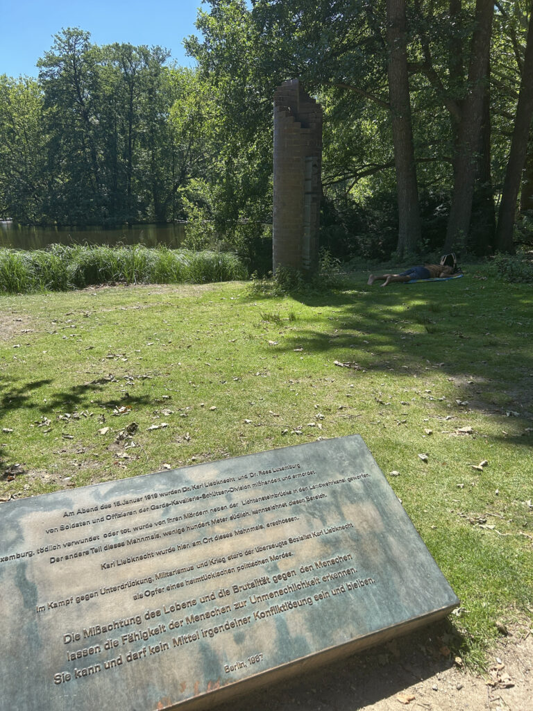The Karl Liebknecht memorial stone at the crime scene of his murder with artwork with his name in in the background.